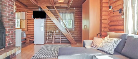 A cozy cabin interior with a living room, kitchen, and a staircase leading to an upper level.