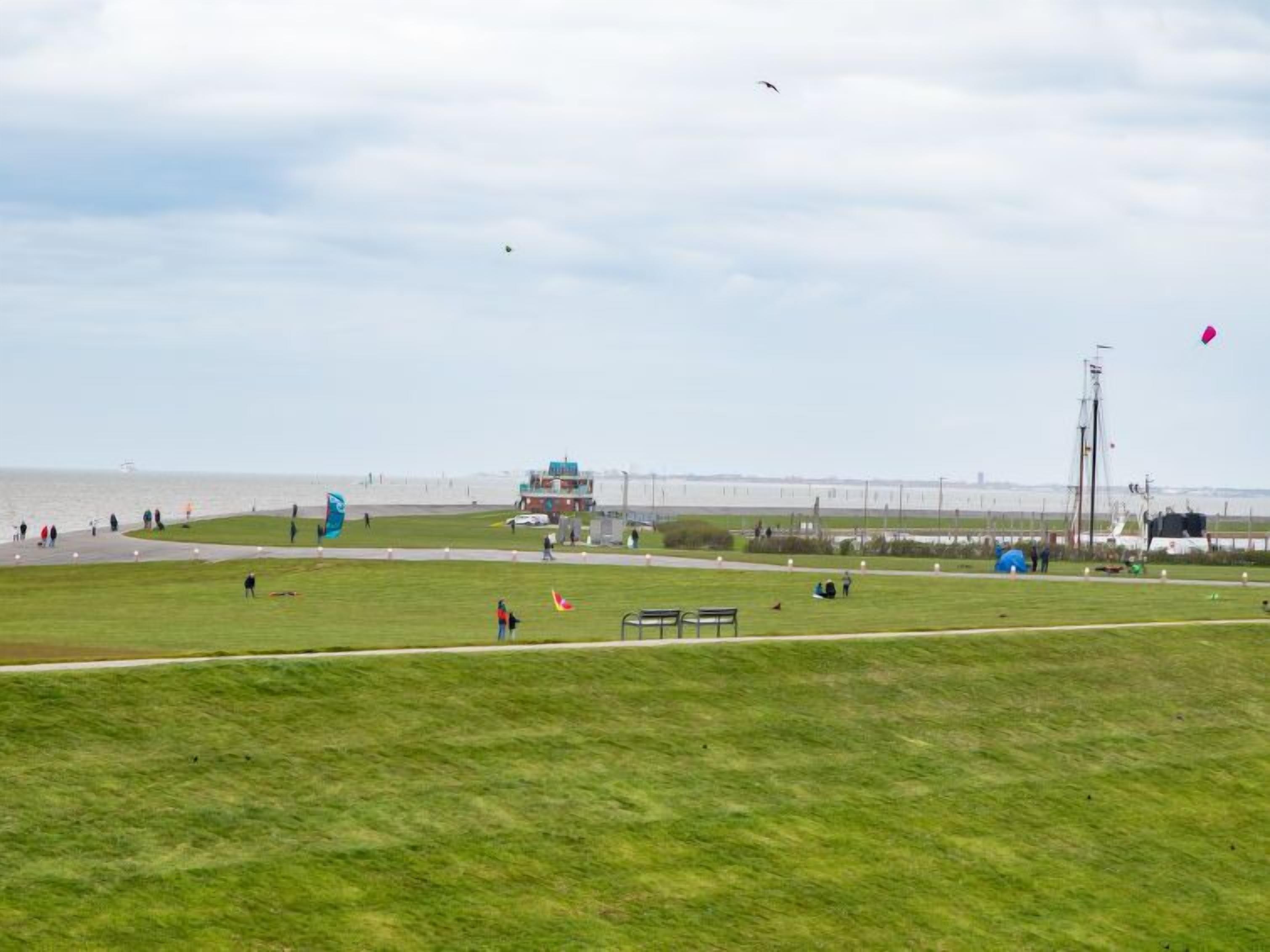 A grassy field with a few people and a building in the distance.