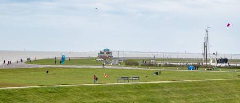 A grassy field with a few people and a building in the distance.