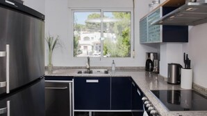 Een moderne keuken met een groot raam, roestvrijstalen apparatuur en donkere kastjes.