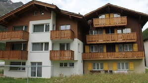 A multi-story building with wooden balconies and a white facade. - Weideli by Interhome (Saas-Grund)