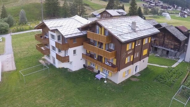 A multi-story hotel with balconies, a ski slope in the background, and a mountainous landscape. - Weideli by Interhome (Saas-Grund)