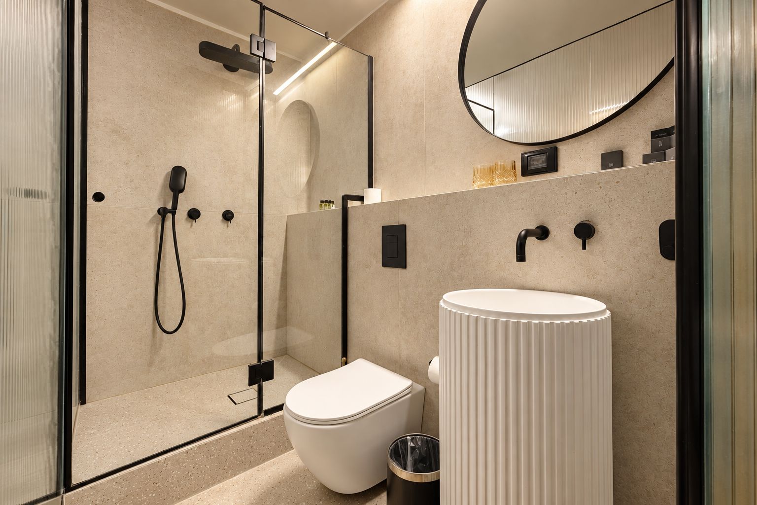 Un baño moderno con ducha envuelta en vidrio, inodoro blanco y espejo redondo.