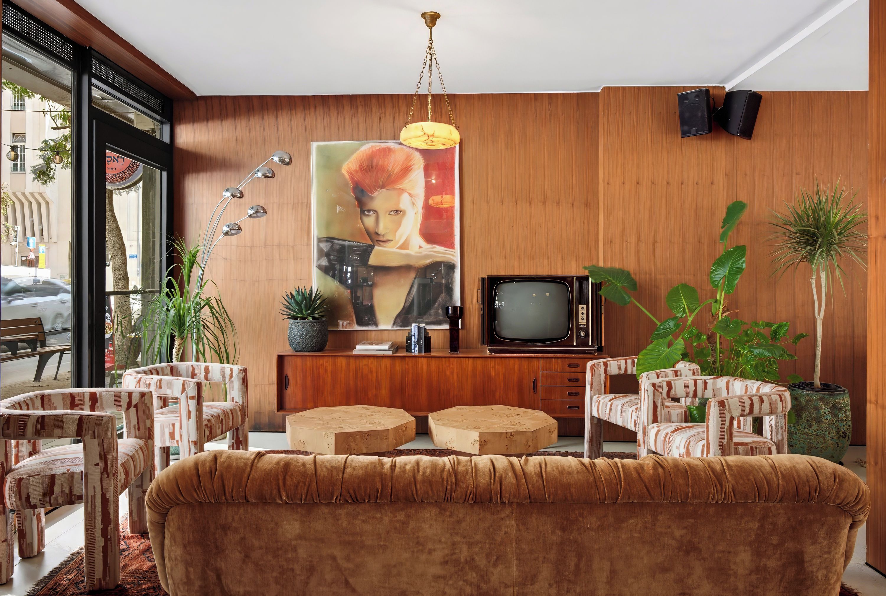 A modern living room with a sofa, chairs, a television, and a large painting on the wall.