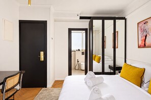 A hotel room with a bed, a desk, a chair, a bathroom, and a mirror. - Theodor Rothschild Tel-Aviv (Tel Aviv)