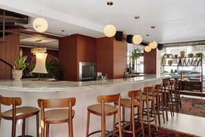 A modern bar area with wooden chairs, a marble countertop, and pendant lighting. - Theodor Rothschild Tel-Aviv (Tel Aviv)