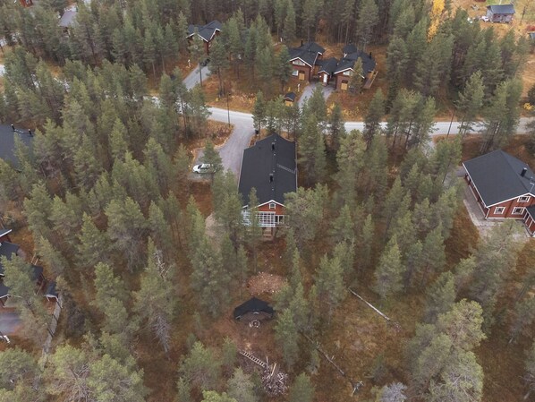 Vue aérienne d’un quartier résidentiel composé de nombreuses maisons, entouré d’une forêt dense.