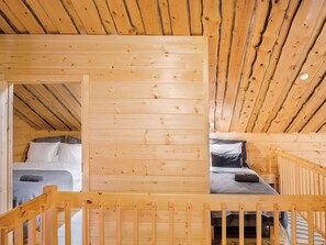 Ein Holzhütten-Innenraum mit zwei Schlafzimmern, jedes mit einem Bett und Kissen.