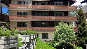 A multi-story building with balconies, named "Nikado," surrounded by greenery and mountains in the background. - Apartment Mikado by Interhome (Saas-Fee)