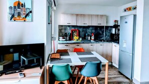 A modern kitchen with wooden cabinets, a stainless steel refrigerator, and a dining area with a table and chairs. - T2 air-conditioned sea view, WIFI, swimming pool and parking (Sète)