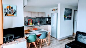 A modern living room with a TV, sofa, and dining area. - T2 air-conditioned sea view, WIFI, swimming pool and parking (Sète)