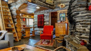 A log cabin interior with a red armchair, wooden furniture, a fireplace, and a ladder. - Kelo-ville by Interhome (Sodankylä)