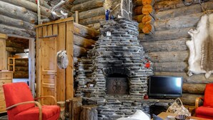 A log cabin interior with a stone fireplace, wooden furniture, and a television. - Kelo-ville by Interhome (Sodankylä)
