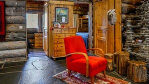 A log cabin interior with a red chair, wooden furniture, and stone walls. - Kelo-ville by Interhome (Sodankyl ä)