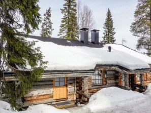 A log cabin with a snow-covered roof, a chimney, and a window with shutters. - Kelo-ville by Interhome (Sodankylä)