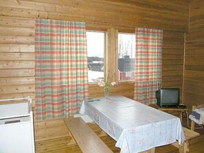 A cabin with wooden walls, a table with a tablecloth, a television, and plaid curtains. - Riitula by Interhome (Taivalkoski)