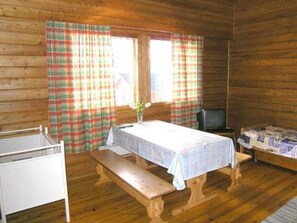 A wooden cabin room with a bed, a table with a vase, and plaid curtains. - Riitula by Interhome (Taivalkoski)