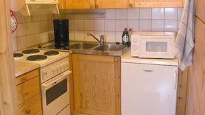 Una cocina compacta con armarios de madera, estufa, microondas y fregadero.