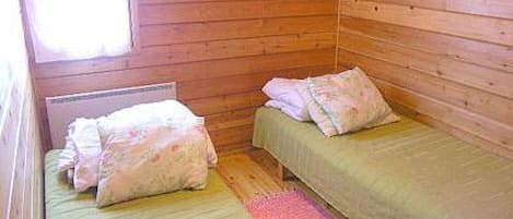 Een kleine kamer met een enkel bed, houten wanden en een raam.