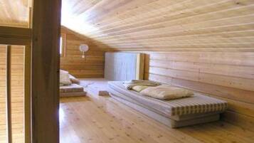 A room with wooden walls and floors, a bed with pillows, and a window.