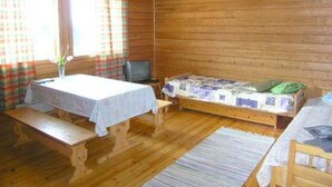 Una habitación de cabaña de madera con una cama, una mesa pequeña y un banco.
