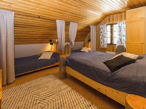 A room with two beds, wooden flooring, and a window with curtains. - Örtsylä b by Interhome (Salla)
