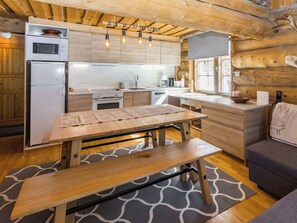 A rustic kitchen with wooden cabinets, a built-in oven, and a dining area with a bench.