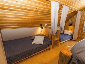 A wooden cabin with two single beds, a small table, and a lamp. - Örtsylä b by Interhome (Salla)