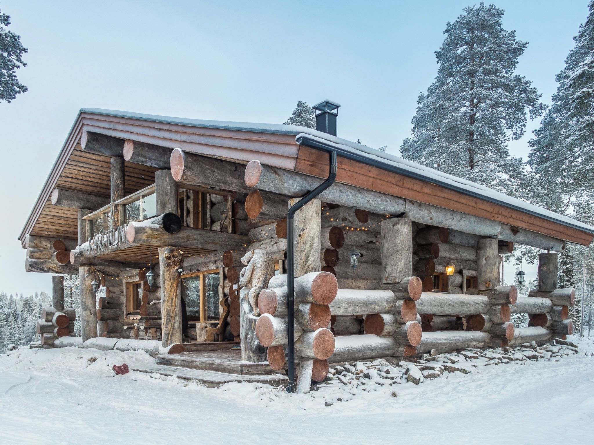 A log cabin with a balcony, surrounded by snow.