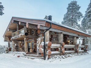 A log cabin with a balcony, surrounded by snow.