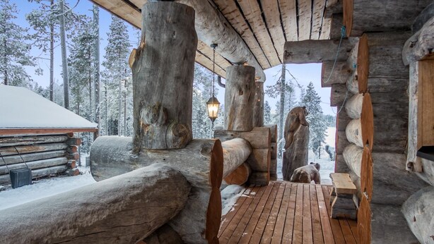 Eine Blockhütte mit einer Holzterrasse und einer Bärenskulptur.