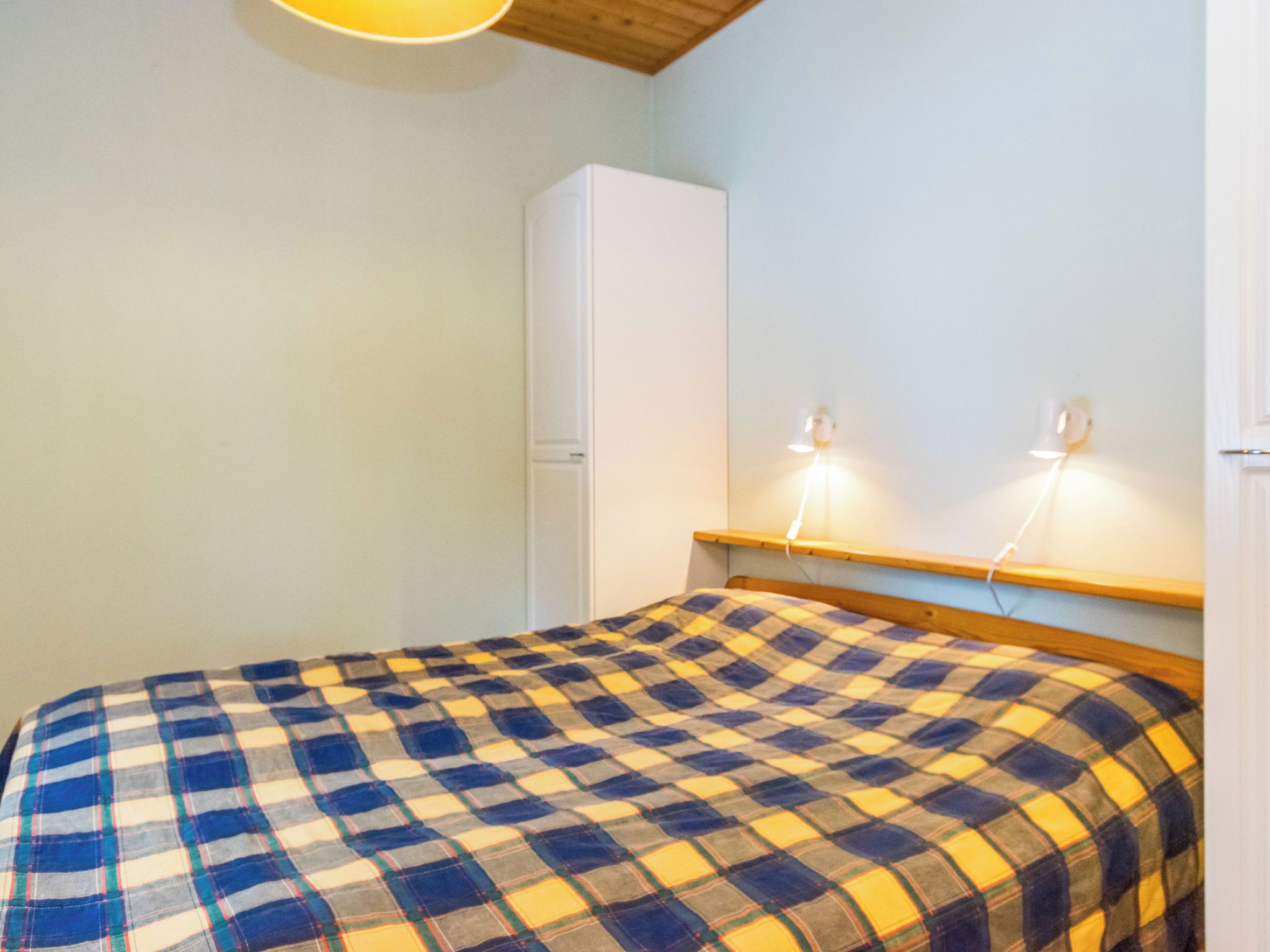 Ein Zimmer mit einem Bett, einem Kleiderschrank und zwei Wandleuchten.