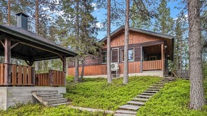 A cabin with a wooden exterior, a covered porch, and a staircase leading to the entrance. - Ruskatupa by Interhome (Kuusamo)