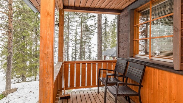 A wooden deck with a bench, surrounded by snow and trees. - Ruskatupa by Interhome (Kuusamo)