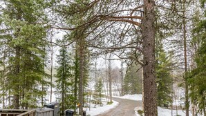 A forested area with a dirt path leading through trees, a wooden structure on the left, and a snow-covered ground. - Ruskatupa by Interhome (Kuusamo)