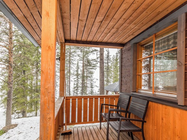 A wooden deck with a railing, a bench, and a window with blinds. - Ruskatupa by Interhome (Kuusamo)