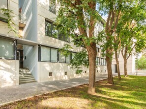 A modern building with a flat facade, large windows, and a tree-lined pathway.