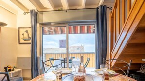 A dining table set with plates, cutlery, and a bottle of wine, with a view of a building through a window. - Le Capitole by Interhome (Fréjus)