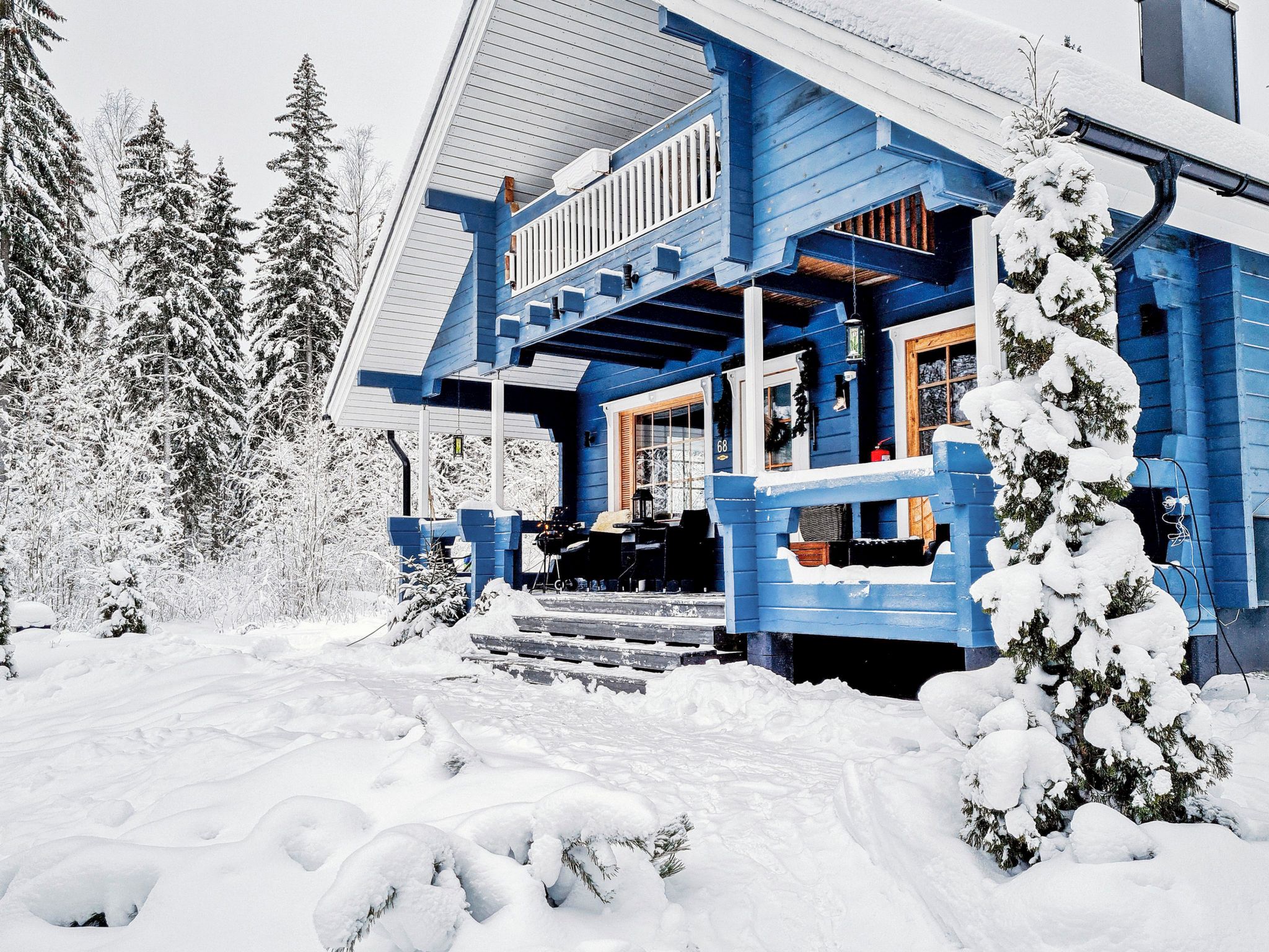 Un edificio azul con un porche, rodeado de árboles cubiertos de nieve.