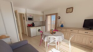 Um espaço compacto com cozinha compacta, área de refeições e sofá.