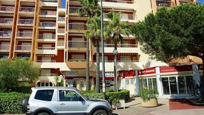 Um hotel com vários andares, varandas, palmeiras e um restaurante chamado "Le Key Biscotine".
