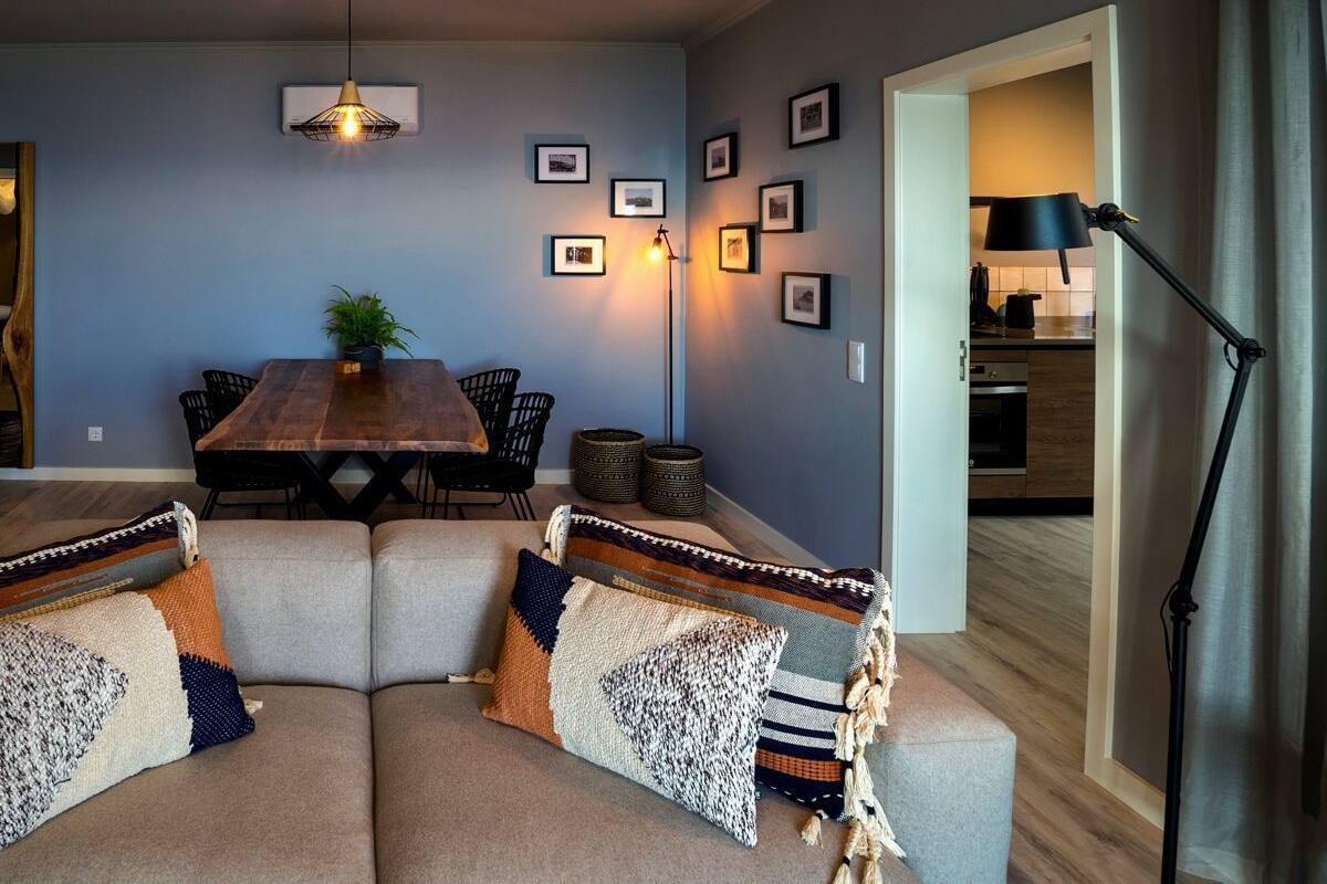 Ein modernes Wohnzimmer mit einem Holzesstisch, gepolsterten Sitzmöglichkeiten und einer Stehlampe.