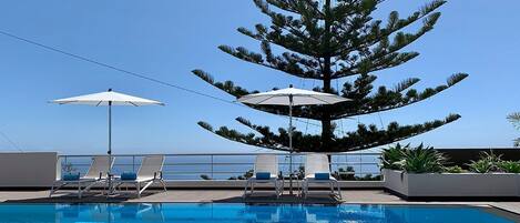 Una piscina al aire libre, sillones reclinables de piscina