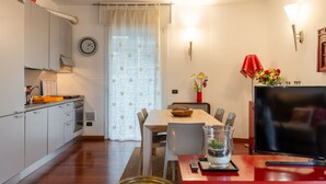 A modern kitchen with a dining area, a TV, and a clock on the wall.