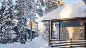 Une cabane dotée d’un porche abrité et surplombant un paysage enneigé.