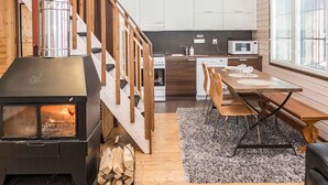 Une cuisine moderne avec des meubles en bois, une cuisinière encastrée et un coin repas comprenant une table et des chaises.
