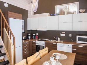A compact kitchen with a refrigerator, stove, microwave, and a dining area with a table and chairs.