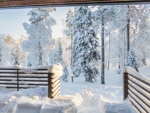 A snowy outdoor area with a bench and a pathway leading through a forest. - Saukkotupa by Interhome (Kuusamo)
