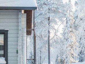 A house with a snow-covered exterior, a visible mailbox, and a street sign indicating a residential area.