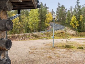 A gravel parking area with a lamp post and a wooden structure with logs.